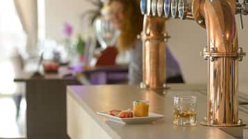 Une cuisine moderne avec un robinet en cuivre et un verre de jus d’orange posé sur le plan de travail.