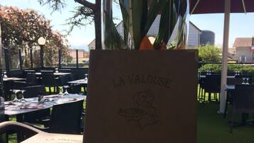A restaurant named "La Valouse" with outdoor seating and a decorative glass vase on the table.