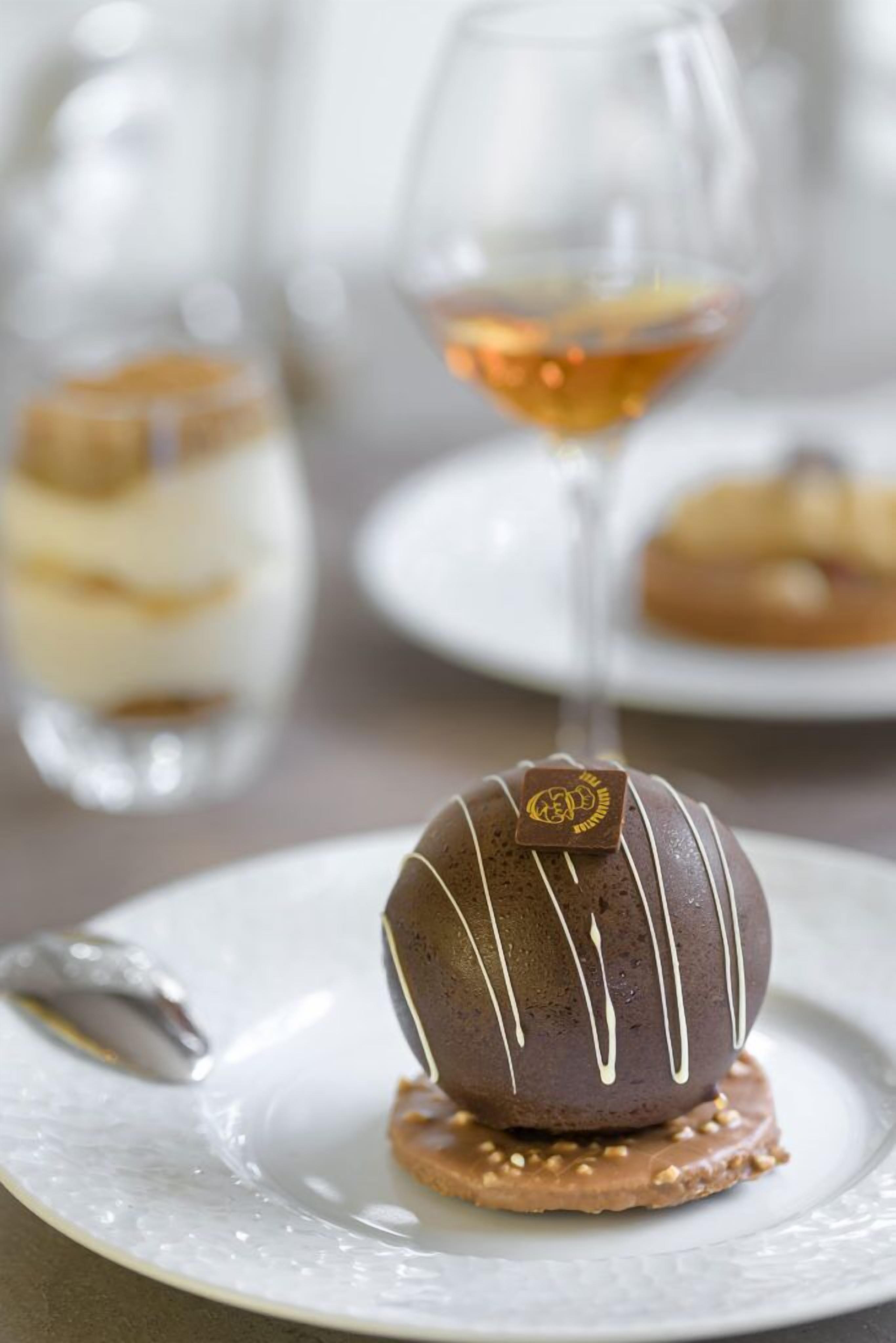 Un postre en un plato con una bebida en un vaso transparente al fondo.