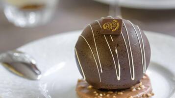A dessert on a plate with a clear glass of a beverage in the background.