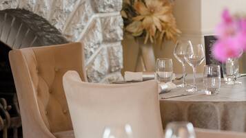 A restaurant interior with a stone fireplace, a table set with wine glasses, and a menu board.