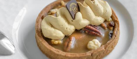 A dessert with whipped cream, pecans, and a chocolate piece on a plate.