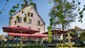 A building with outdoor seating and a fountain. - Hôtel Le Vouglans (Orgelet)