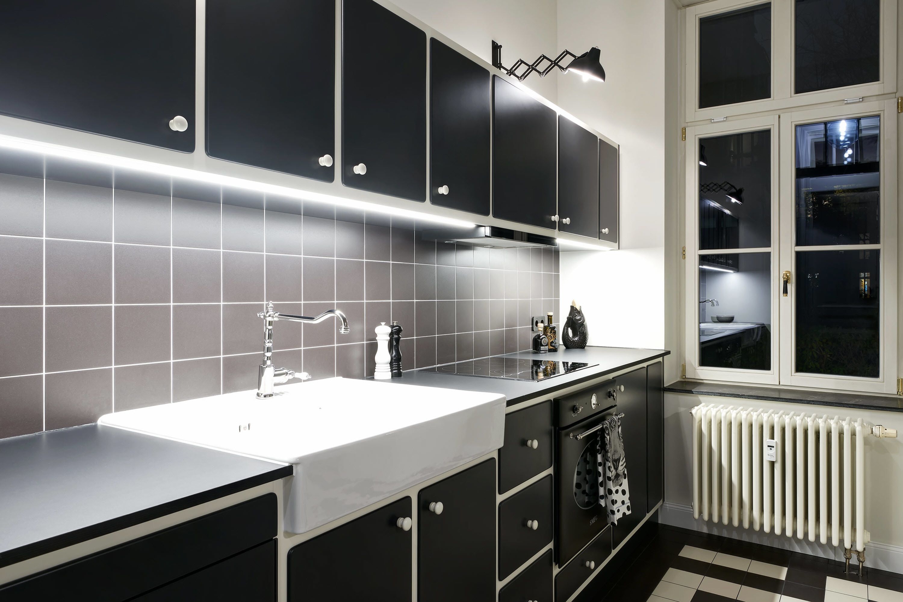 A modern kitchen with a white countertop, black cabinets, and a window with a view of the outside.
