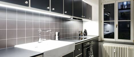 A modern kitchen with a white countertop, black cabinets, and a window with a view of the outside.
