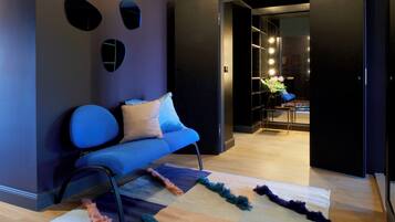 Ein modernes Wohnzimmer mit einem blauen Sofa, einem gemusterten Teppich und einer dunklen Wand mit drei runden Spiegeln.