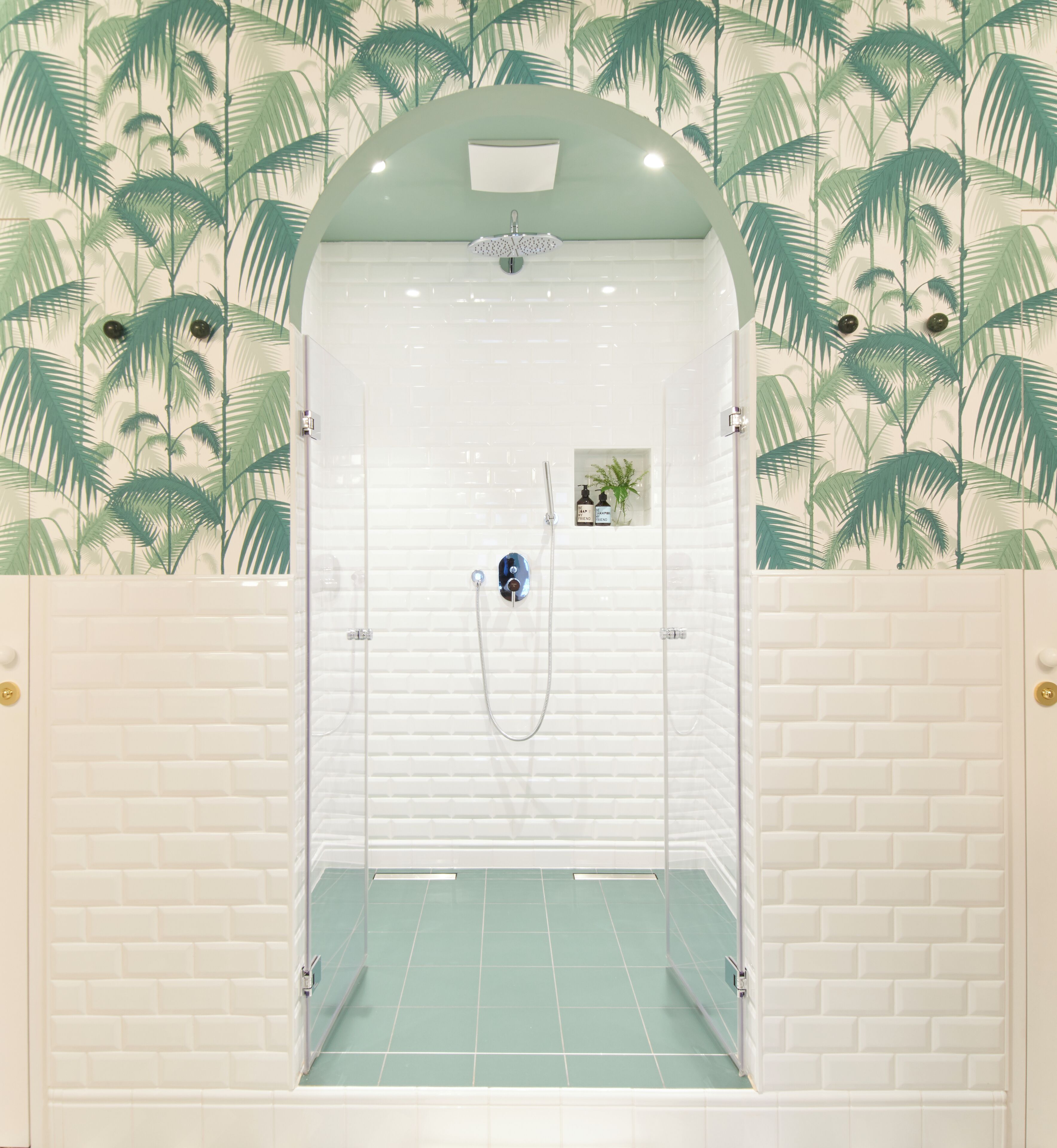 A bathroom with a shower, white tiled walls, and a green floor.