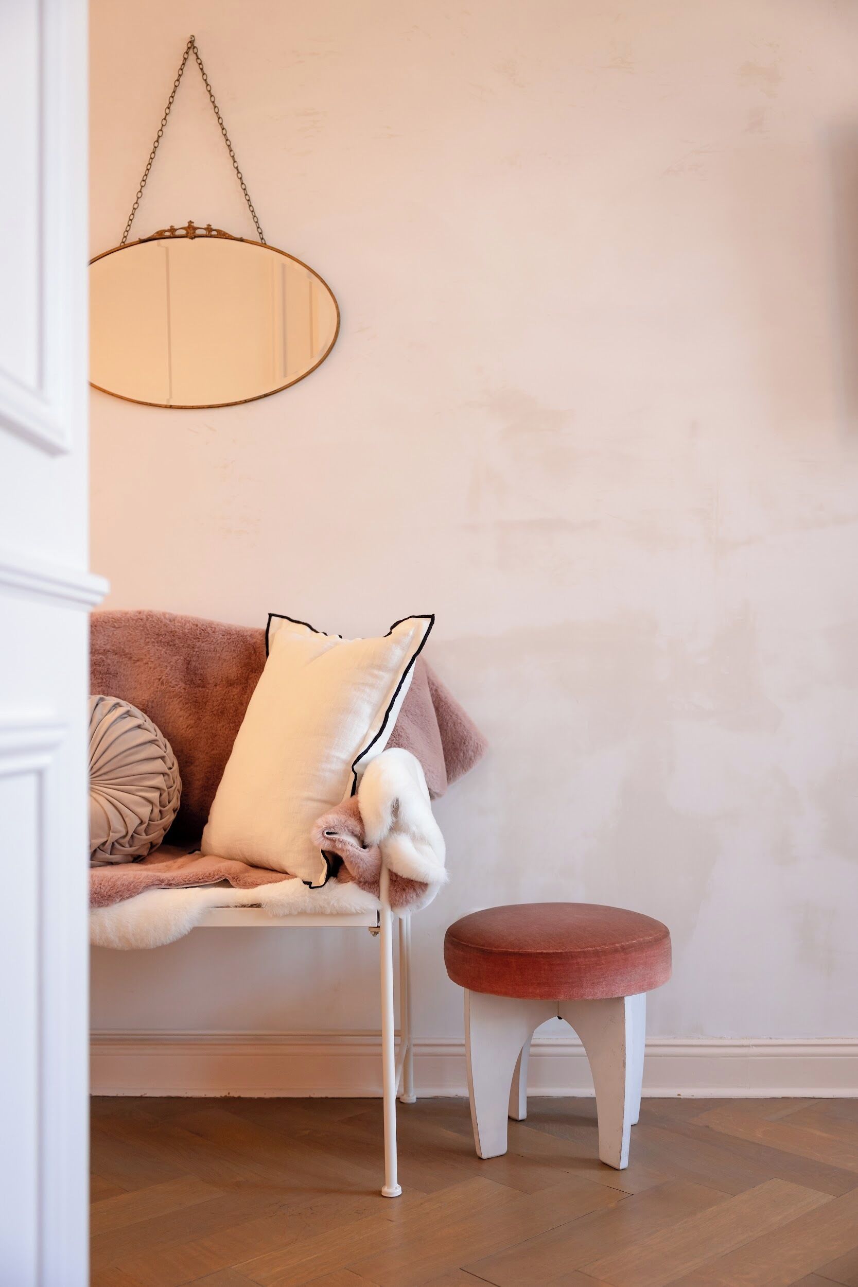 Una habitación acogedora con un sofá marrón, una silla blanca y un taburete pequeño rojo.