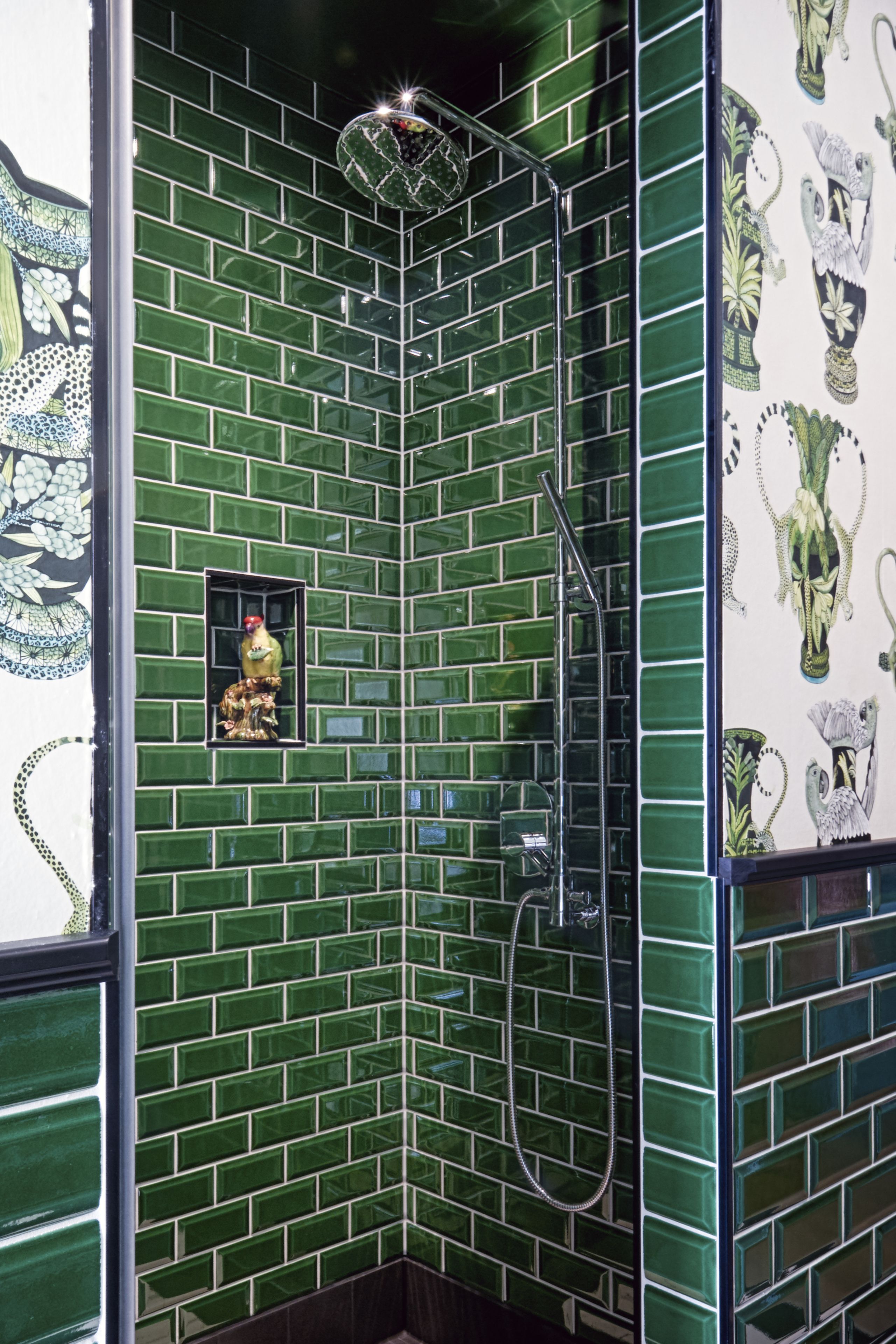 Una ducha con mosaicos verdes y un pequeño ventanal decorativo.