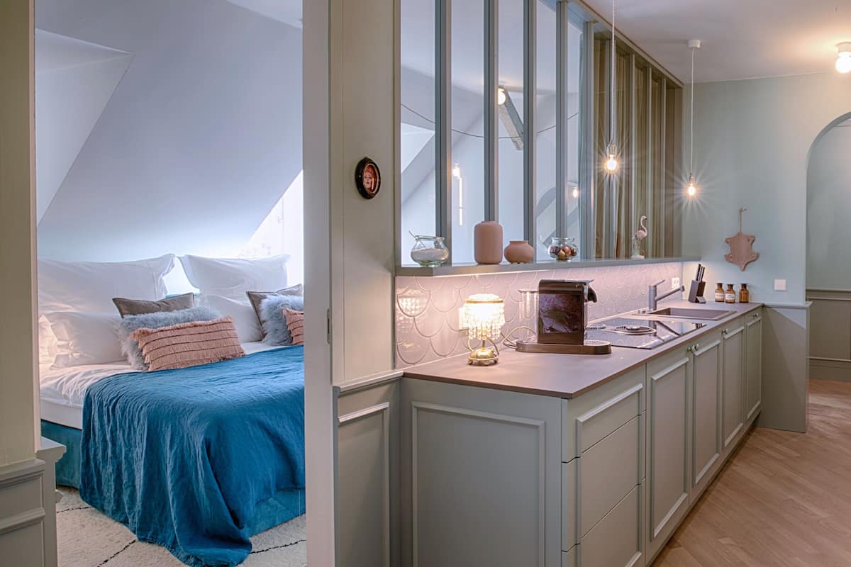 A bedroom with a large bed, a nightstand, and a dresser. There is a window with a view of the sky.