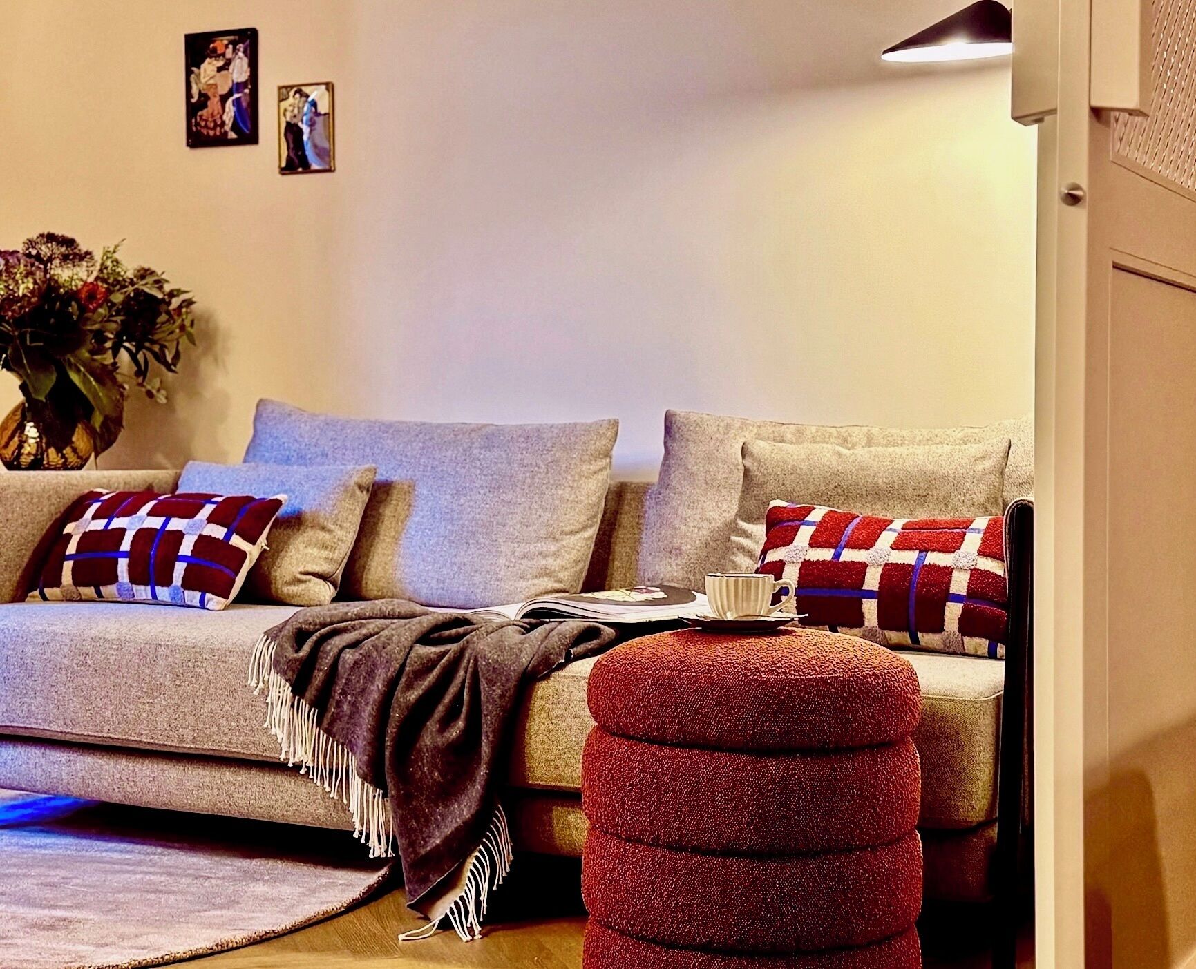 Ein gemütliches Wohnzimmer mit einer Couch, einem Hocker und einem Couchtisch.