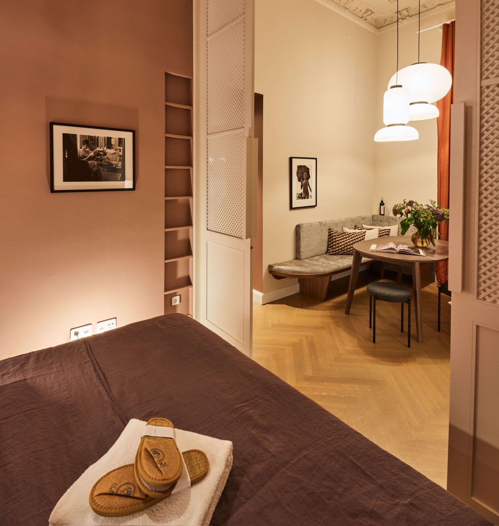 A hotel room with a bed, a small dining area with a table and chairs, a sofa, and a wall-mounted shelf.