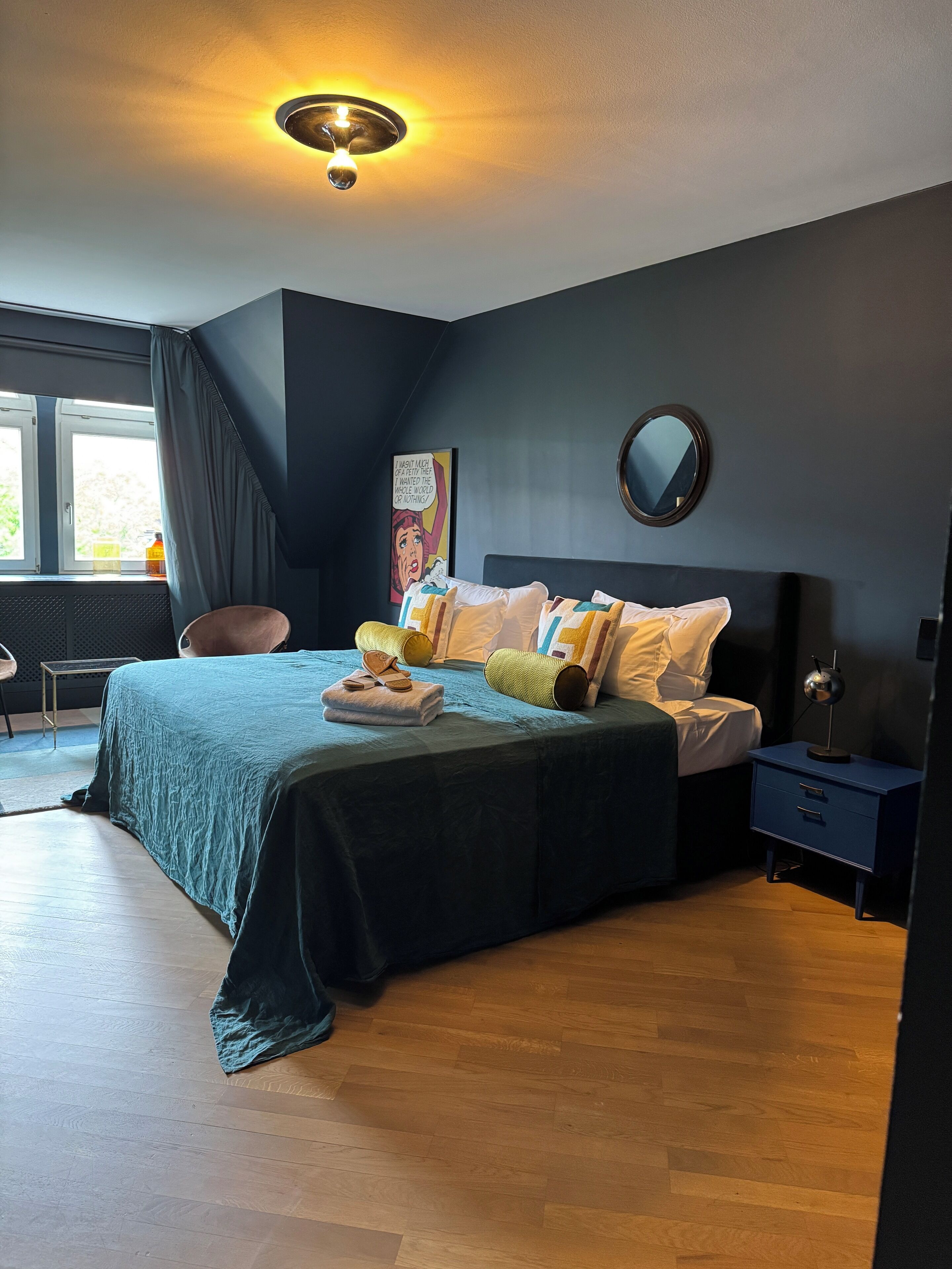 A bedroom with a bed, bedside table, and a window.