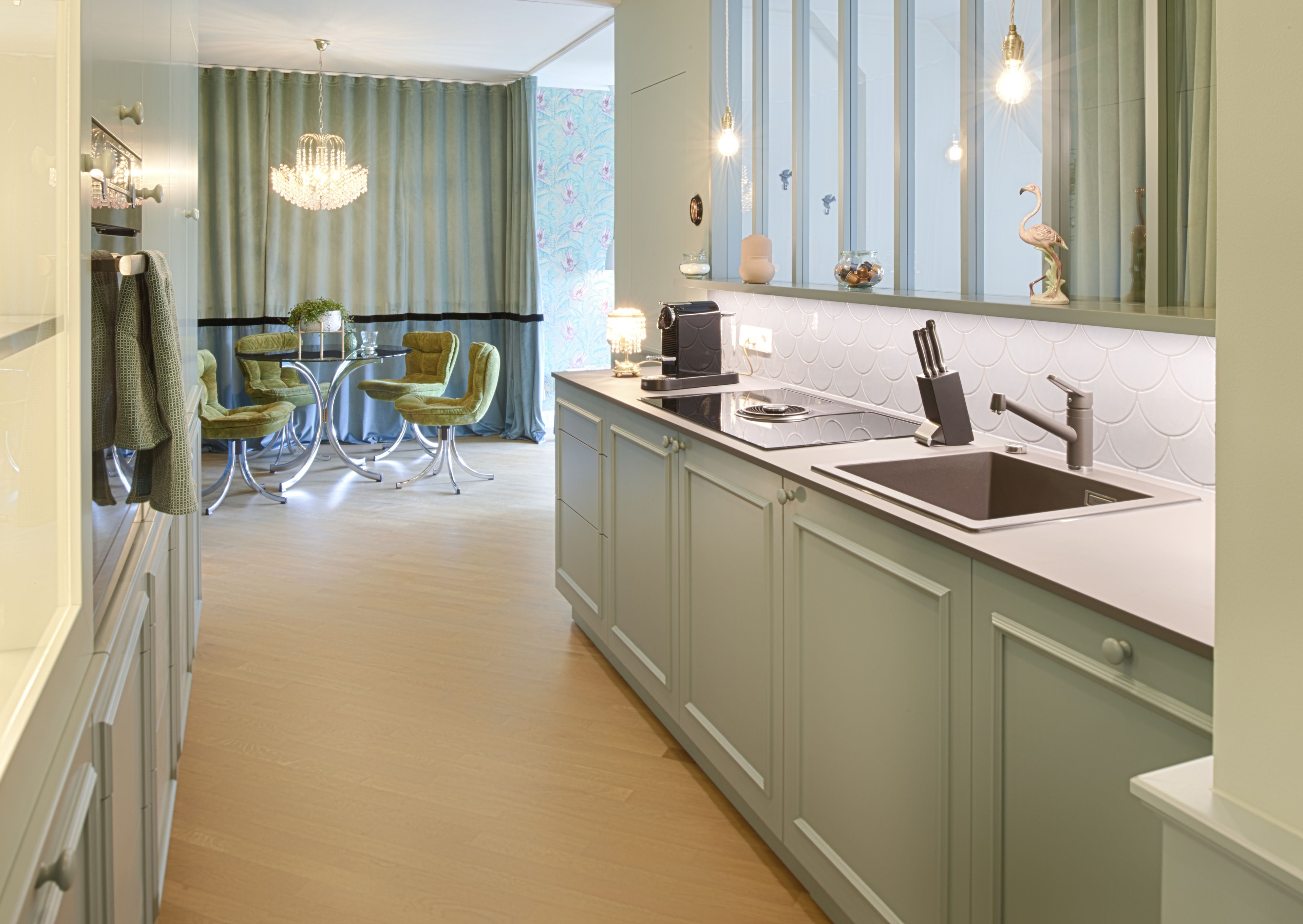 A modern kitchen with a central island, a dining area with a table and chairs, and a large window with curtains.