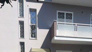 Un bâtiment à deux étages doté d’une cour pavée de pierres, d’une entrée fermée par un portail et de grilles décoratives aux fenêtres.