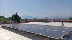 Un toit équipé de panneaux solaires, d’une antenne parabolique et d’une rambarde rouge.