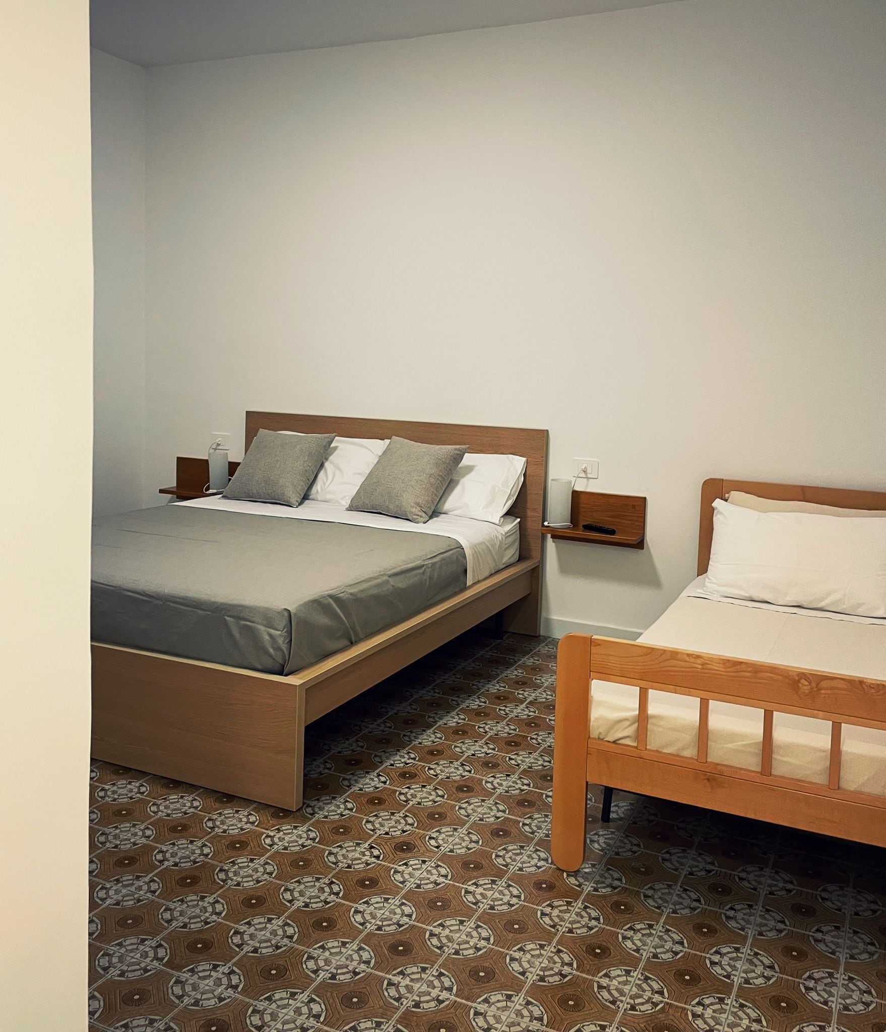 Un dormitorio con dos camas, una mesita de noche y un estante en la pared.