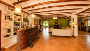 Una habitación amplia con techo de madera, una zona de bar con estantes y un área de estar con chimenea.