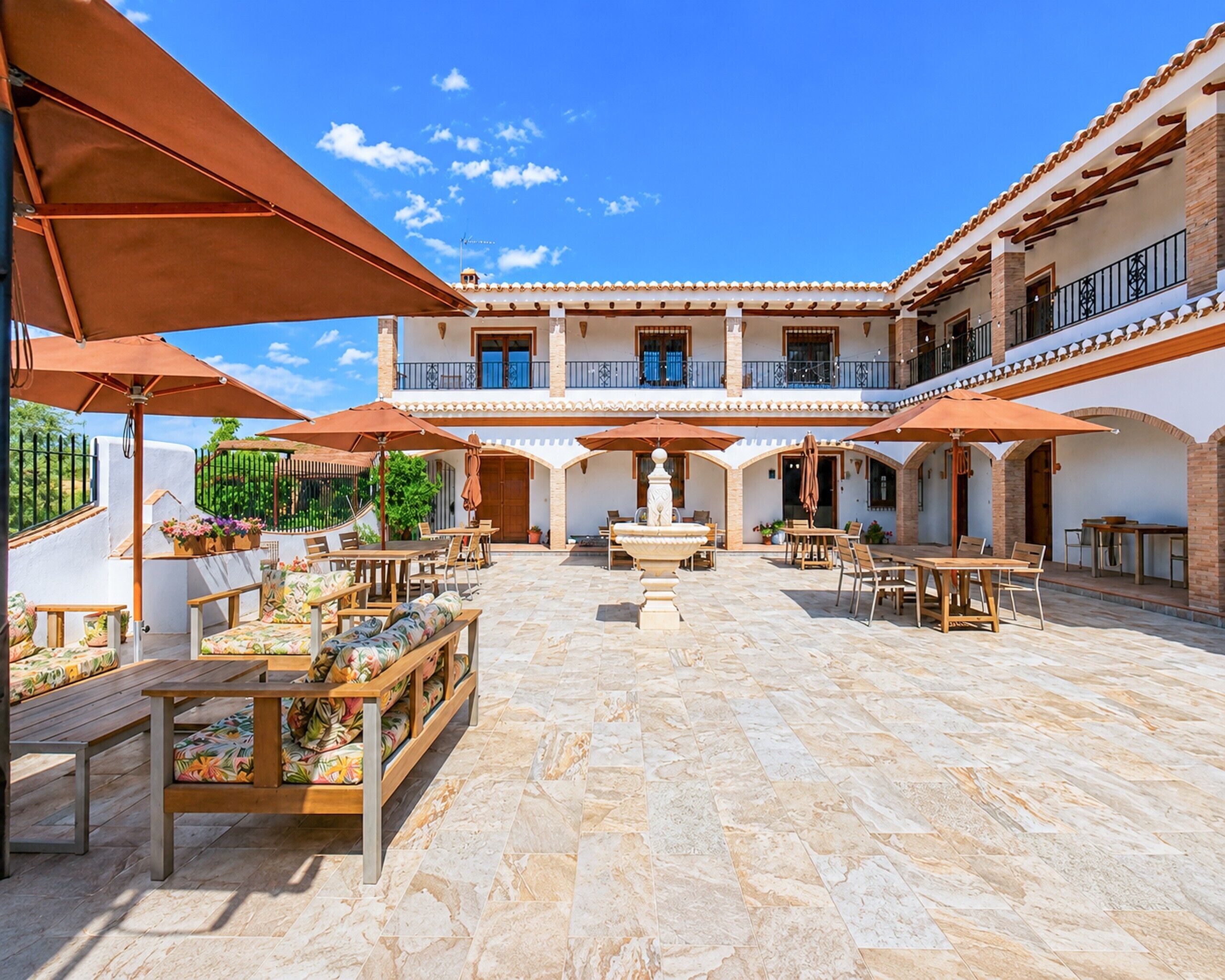 Un patio con mobiliario exterior, una fuente y un edificio con varios balcones.