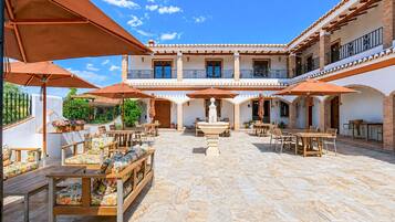 Un patio con mobiliario exterior, una fuente y un edificio con varios balcones.