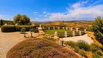 A landscaped garden with a variety of plants and a fenced area with white posts.