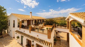 Una casa de dos pisos con un patio, muebles de exterior y vistas al campo.