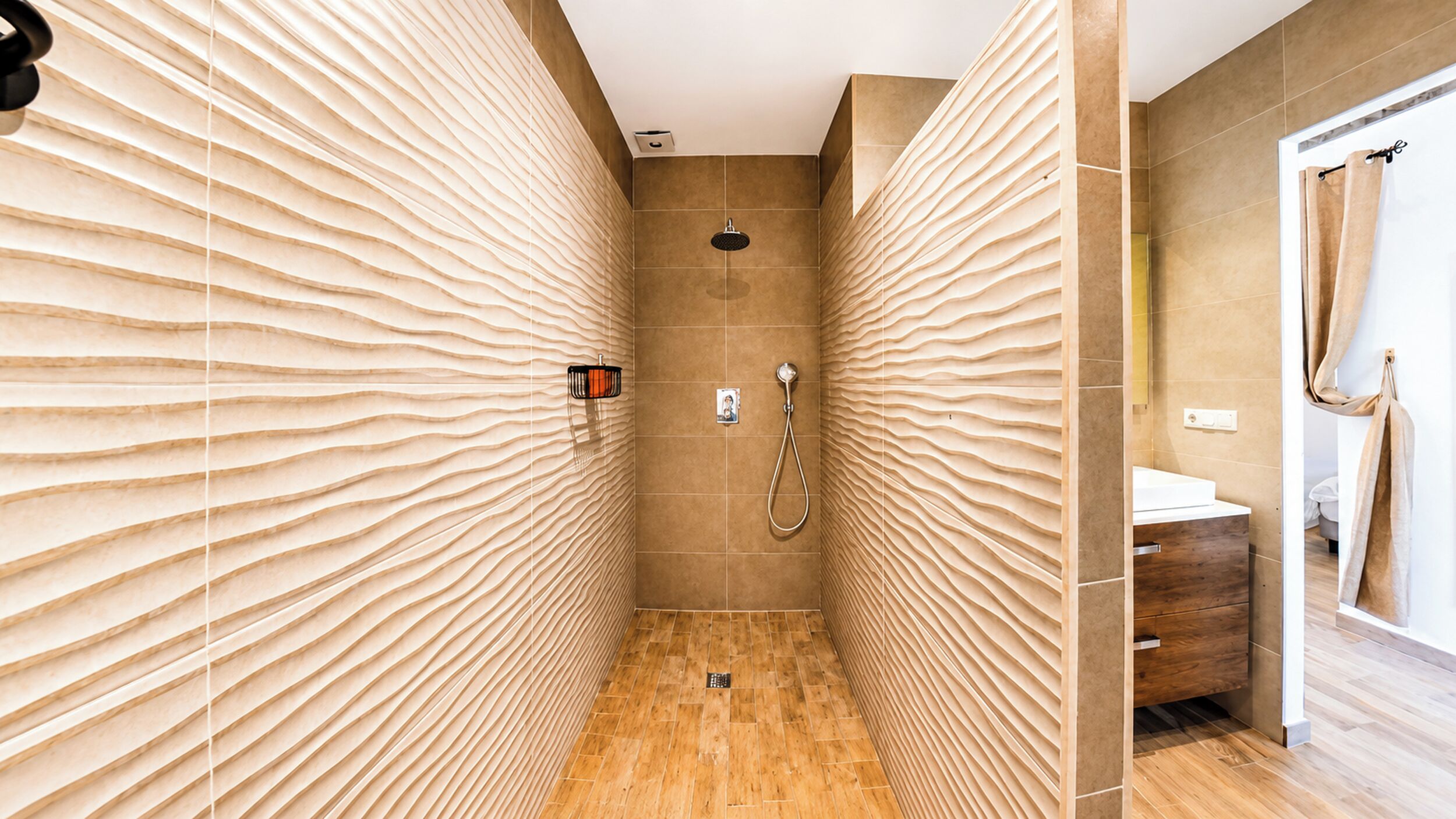 A modern bathroom with a shower, wooden floor, and textured walls.