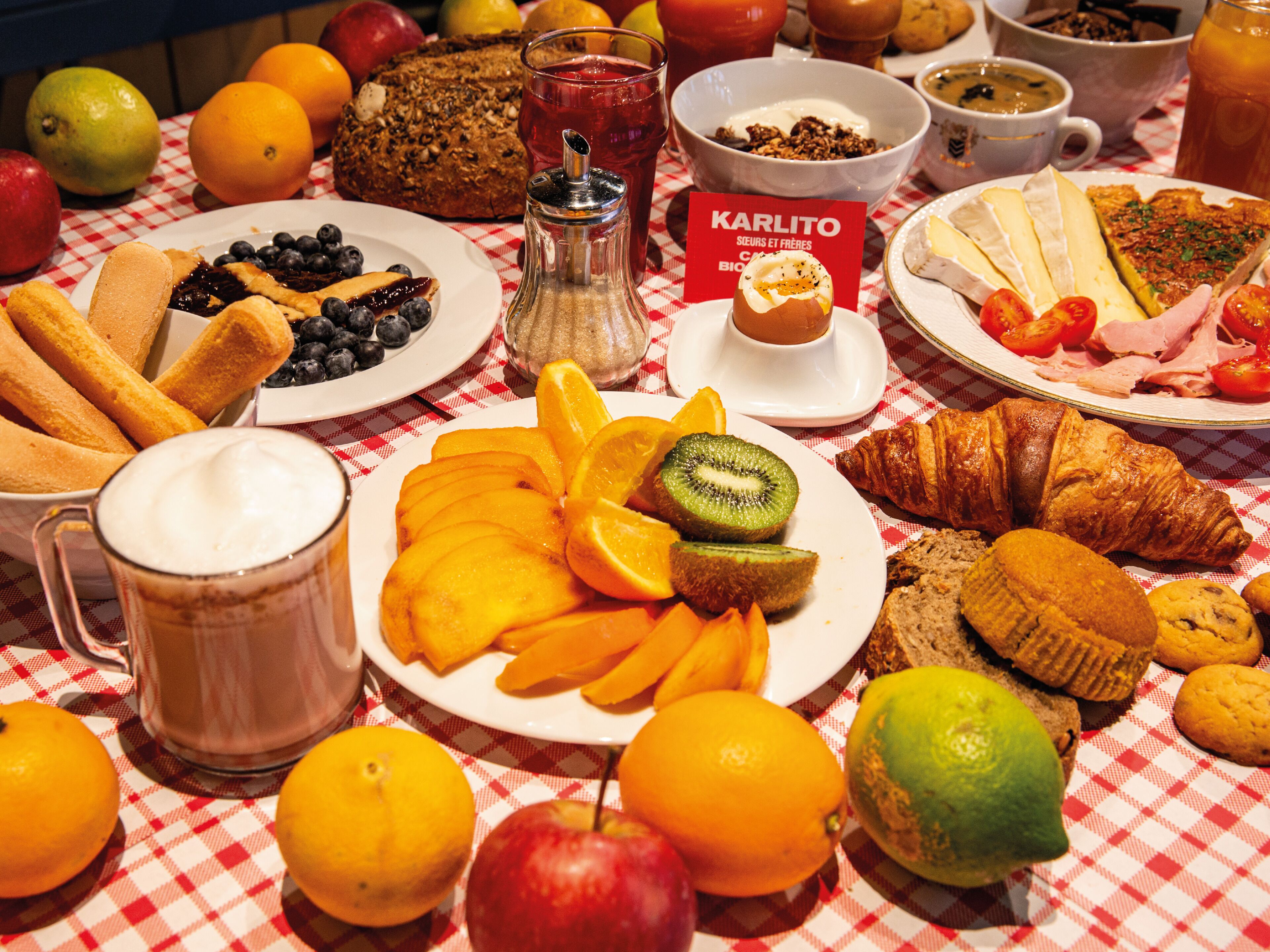 Una mesa de desayuno con diversas frutas, pasteles y bebidas.