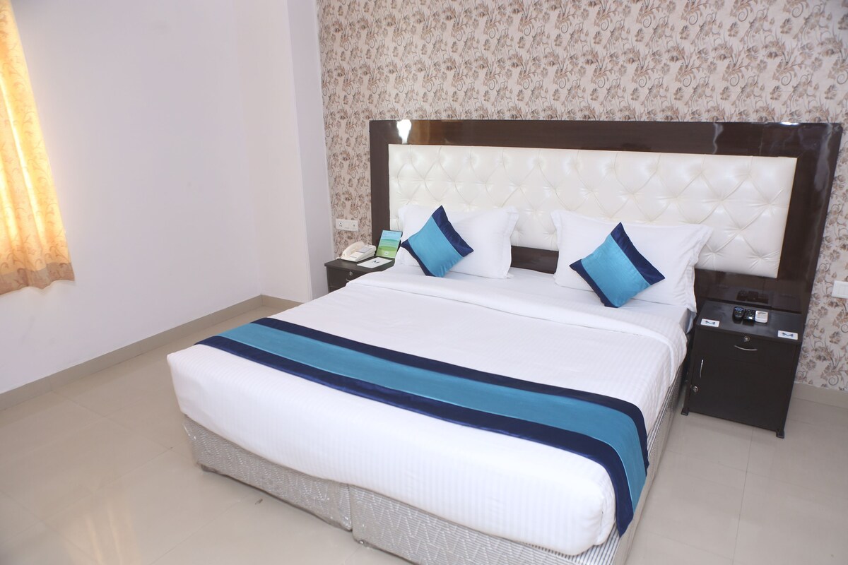 A neatly made bed with a white and blue striped bedspread, a tufted headboard, and two bedside tables with lamps.