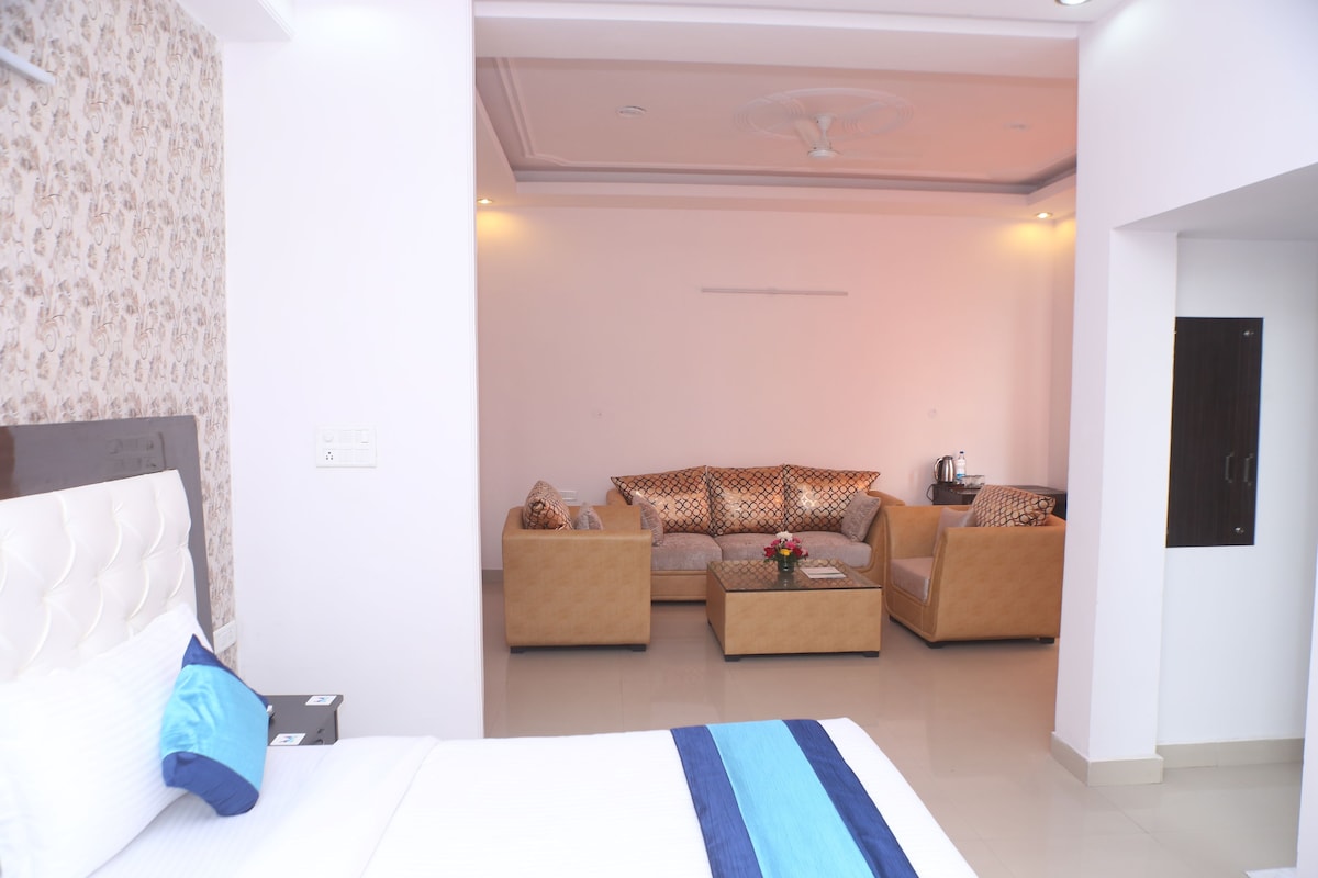 A hotel room with a bed, a sofa, a coffee table, and a television.