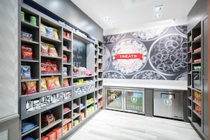 A snack aisle with various packaged snacks and a 'Treats' sign above a display of ice cream. - Hampton Inn & Suites Glenarden/Washington DC (Lanham)