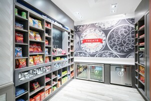 A snack aisle with various packaged snacks and a 'Treats' sign above a display of ice cream.