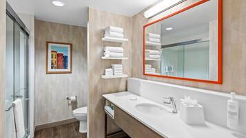 A modern bathroom with a glass shower enclosure, a toilet, a sink with a mirror, and towel racks.