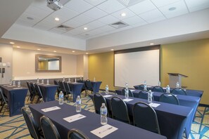 A conference room with tables, chairs, water bottles, a projector, and a screen. - Hampton Inn & Suites Glenarden/Washington DC (Lanham)