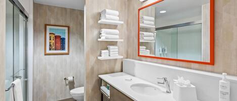 A modern bathroom with a glass shower enclosure, a toilet, a sink with a mirror, and a towel rack.