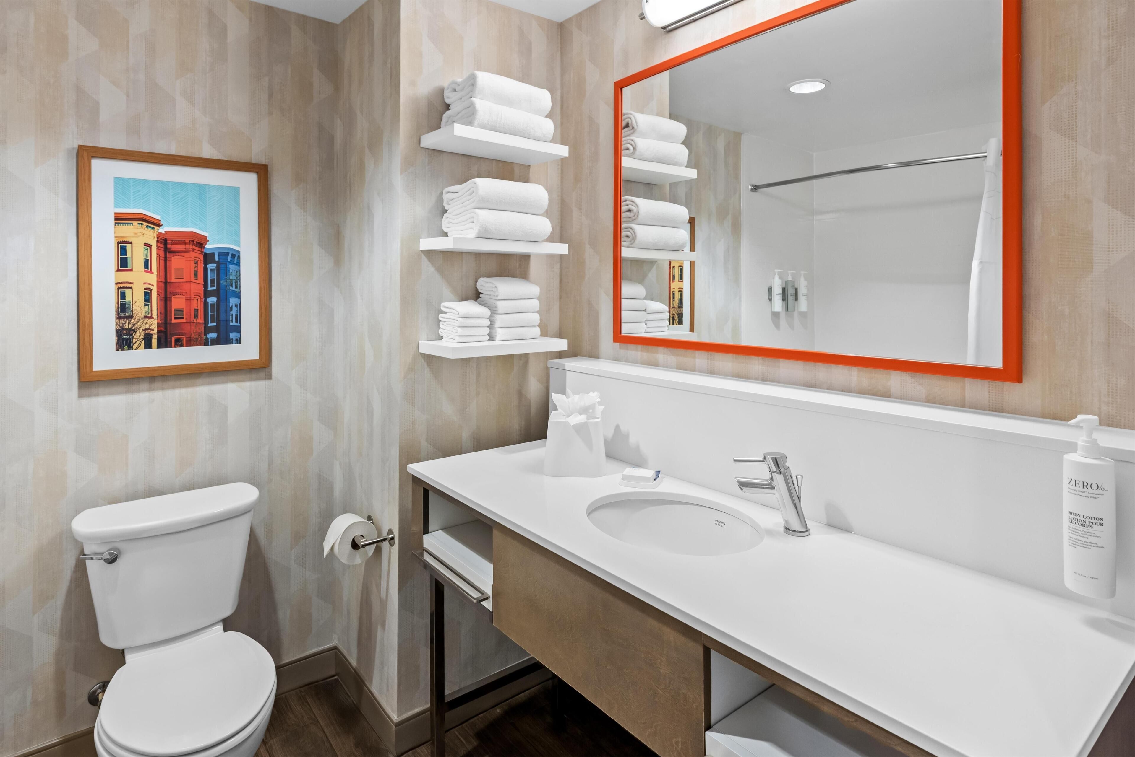 A modern bathroom with a toilet, sink, and towel racks.