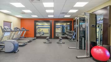 A gym with treadmills, weight machines, and a red exercise ball.