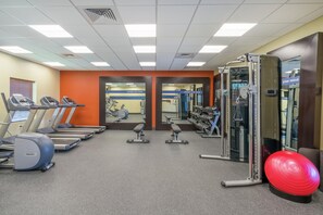 A gym with treadmills, weight machines, and a red exercise ball. - Hampton Inn & Suites Glenarden/Washington DC (Lanham)