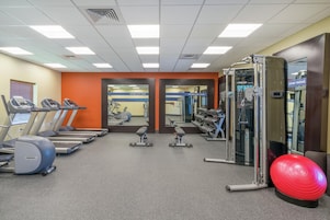 A gym with treadmills, weight machines, and a red exercise ball.