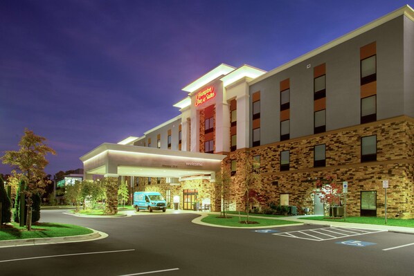 A modern hotel with a stone facade, a blue van parked in front, and a clear sky. - Hampton Inn & Suites Glenarden/Washington DC (Lanham)