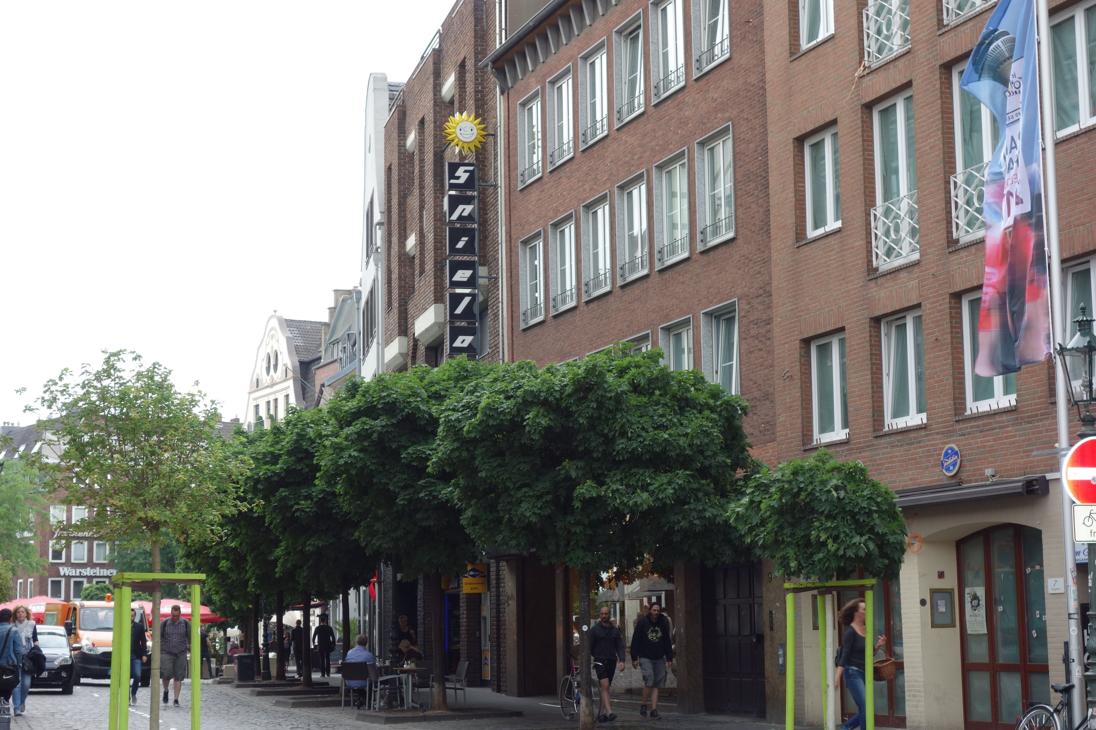 Straßenszene mit einem Gebäude, an dem ein Schild mit der Nummer 5 und einem Sonnensymbol angebracht ist.