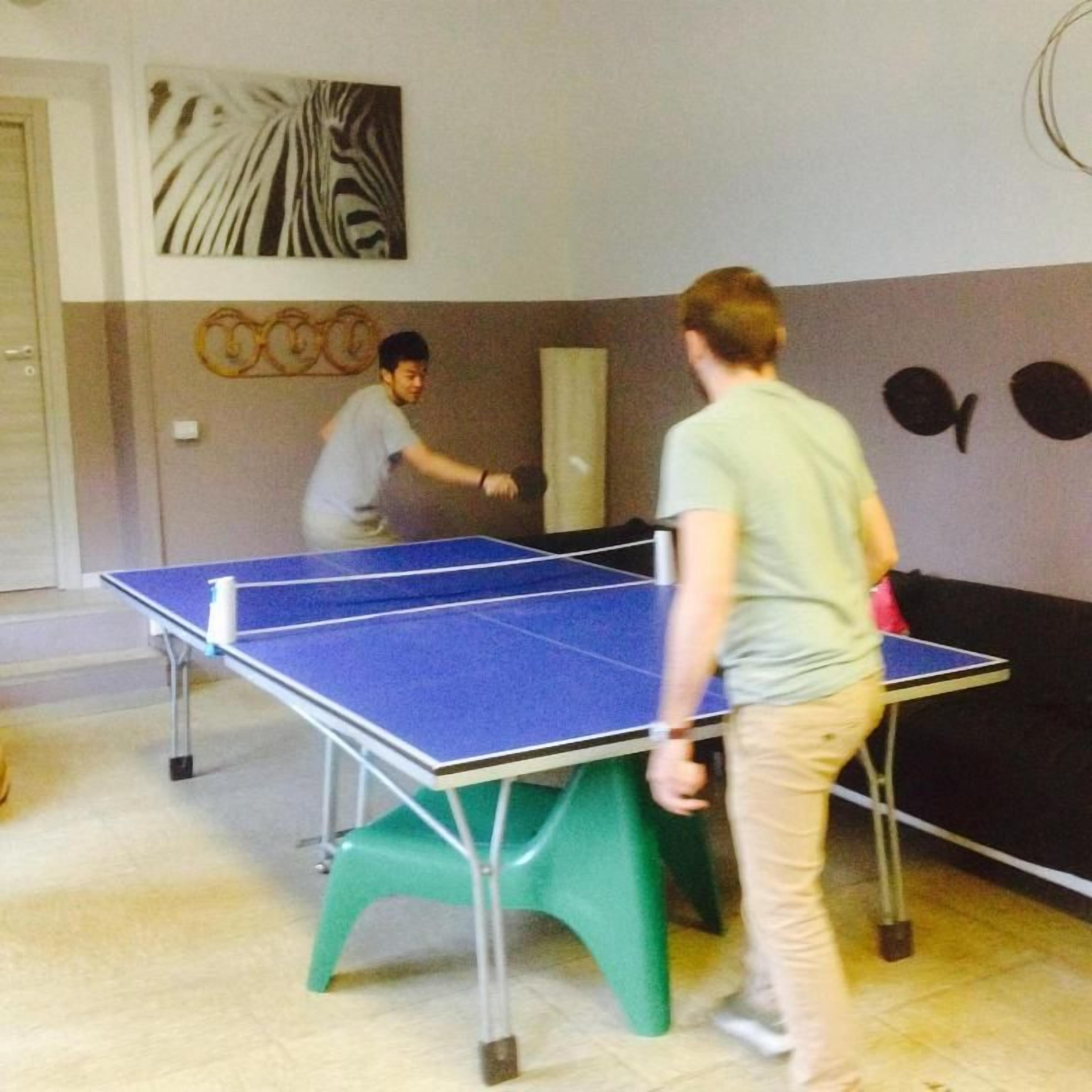 Una habitación con mesa de ping pong, una puerta y una pared con arte abstracto y decoraciones circulares.