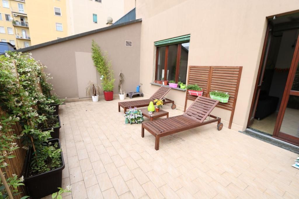 Une terrasse avec deux fauteuils de jardin en bois, une petite table et des plantes en pot.