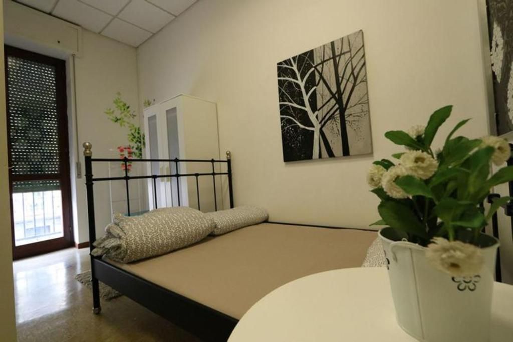 Une chambre à coucher avec un lit, un mur blanc, un tableau et une plante en pot.