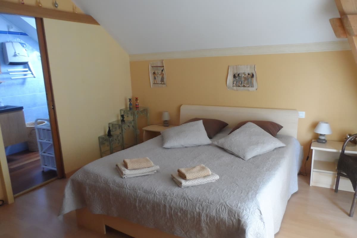 Une chambre à coucher comprenant un lit, deux tables de chevet, une chaise et une petite table.