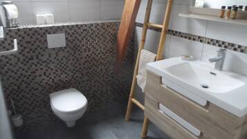 A bathroom with a toilet, a sink, and a shower area.