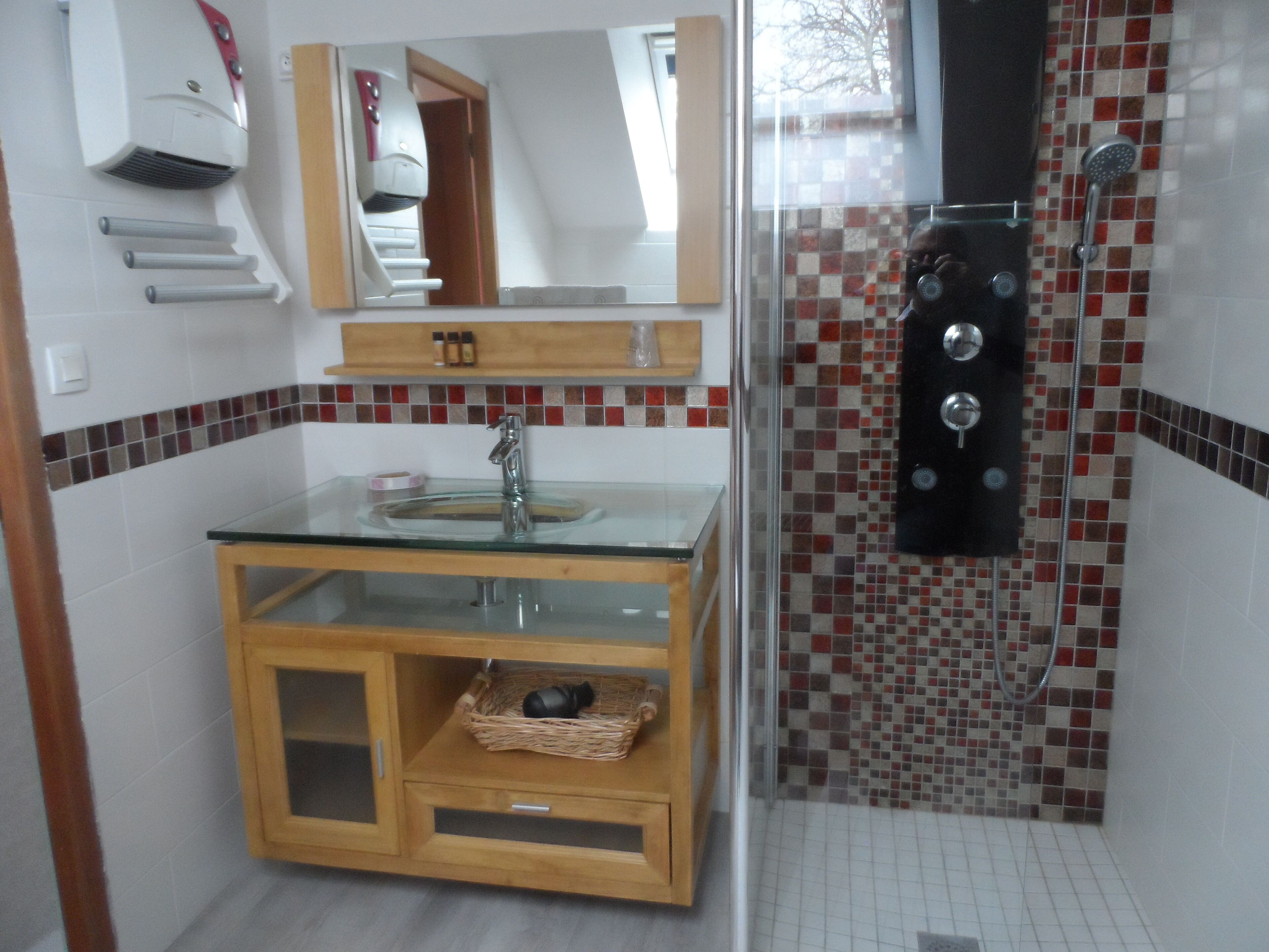 A bathroom with a glass sink, wooden cabinet, and a shower with a tiled wall.