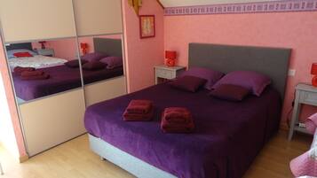 A bedroom with a large bed, two nightstands, a mirror, and a wooden floor.
