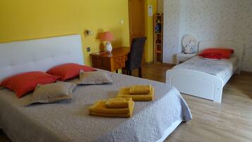 Une chambre d’hôtel avec un grand lit, un lit plus petit, un bureau avec une lampe et une chaise.