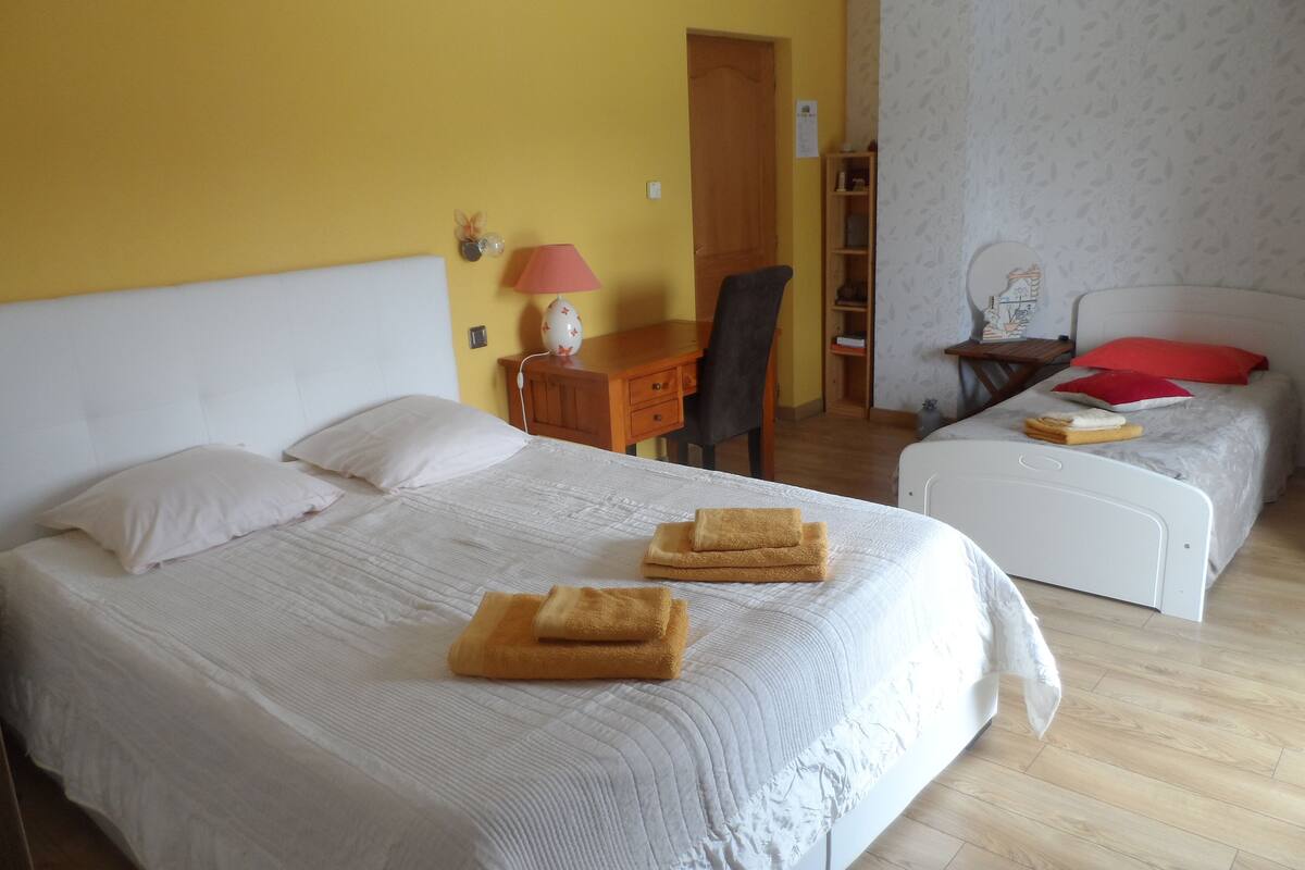 Une chambre d’hôtel avec deux lits, un bureau, une chaise et une petite table avec une lampe.